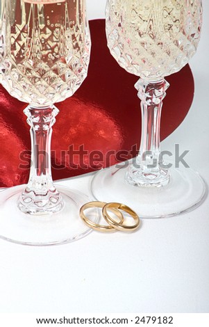 Pair of wedding rings with champagne glasses for toast.