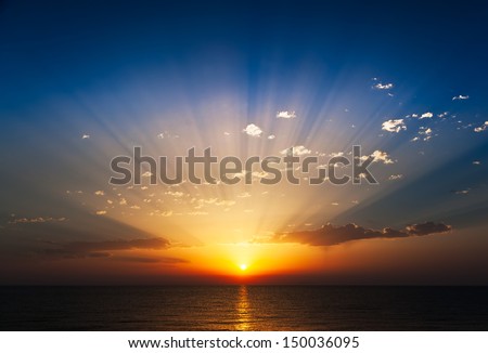 Perfect sunrise on the sea, with radiant rays of sun over a warm colourful horizont.