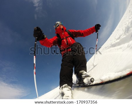 Skier performs a high speed turn on a ski slope. From the ski tip point of view. Sunny winter day. Concepts: vacation, speed, fun.