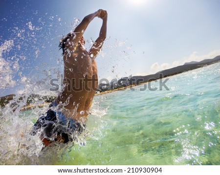 Caucasian young boy jumping in water, playing and having fun. Corsica, France, mediterranean sea, Europe.