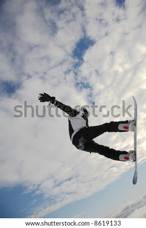Snowboarder launching off a jump; vertical orientation, afternoon light