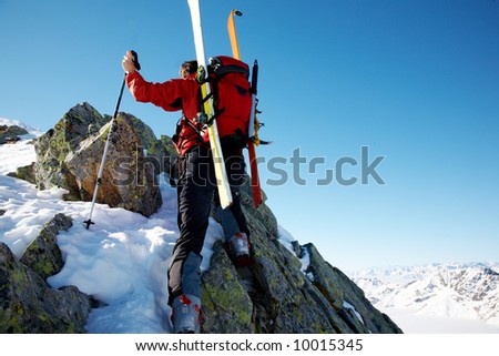 Male ski-climber climbing a rocky ridge; horizontal frame. Italian alps.