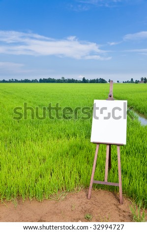 Blank canvas on a wooden easel over a green field. Large copy space on the white canvas. Vertical orientation
