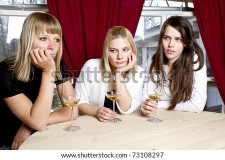 Beautiful young girls having drink in bar holding glasses