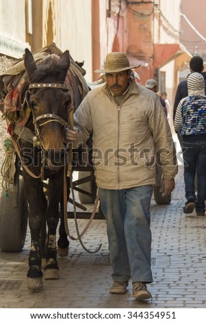 Unidentified Arabic man with horse in a old narrow street of Marrakech in Morocco. 24-02-2015