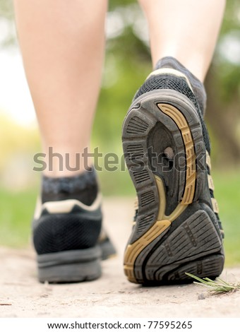 Woman walking on hiking trail in forest, sport shoe closeup