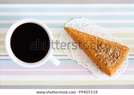Cup of coffee with cake on the colored striped napkin. Top view