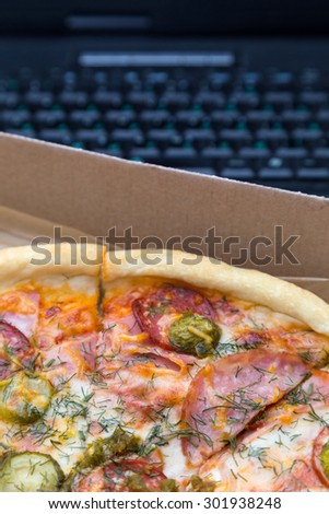 pieces pizza with sausages and bacon in box on laptop keyboard background