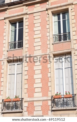 Lovely Paris windows of the pink brick buildings in the Place des Vosges of the Marais district.