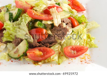 Salad from beef, tomatoes, cucumbers with sauce from olive oil of balsam vinegar on a light plate. A shot horizontal, focus in the center a shot.