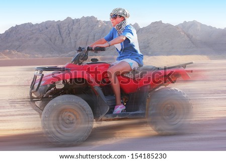 Girl on the ATV goes with high speed on desert