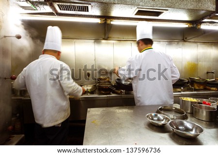 Crowded kitchen, a narrow aisle, working chef.