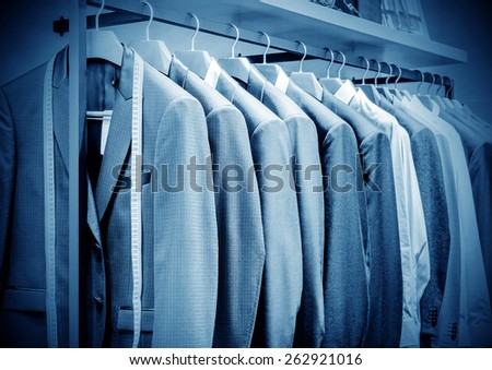 Row of men\'s suits hanging in closet.