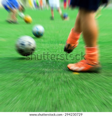 Close-up of little boy playing football on football pitch