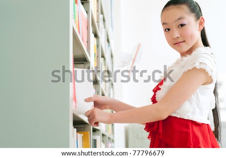 The beautiful girl to study in the library, choose their favorite books.