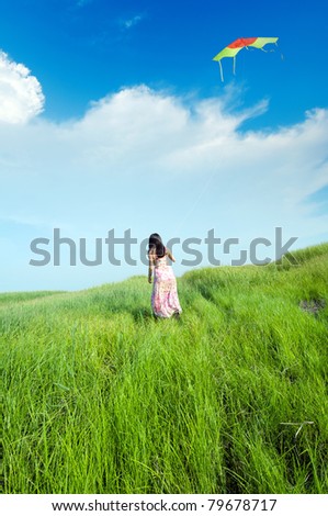 Blue sky, wearing a skirt girl flying a kite in the grasslands.