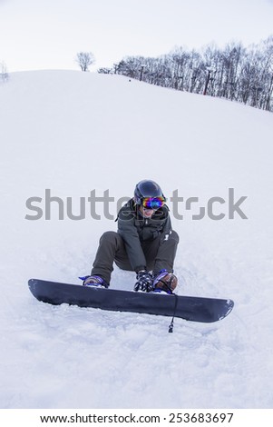 a snowboarder strapping on her snowboard at ski slope