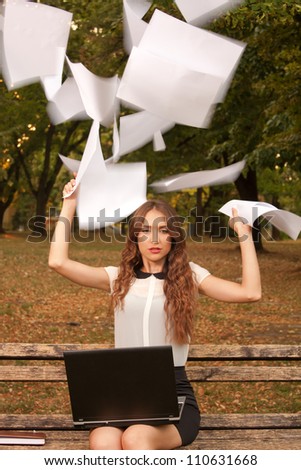 Young businesswoman throwing paper in the air
