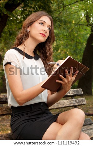 The girl writes her diary in the park