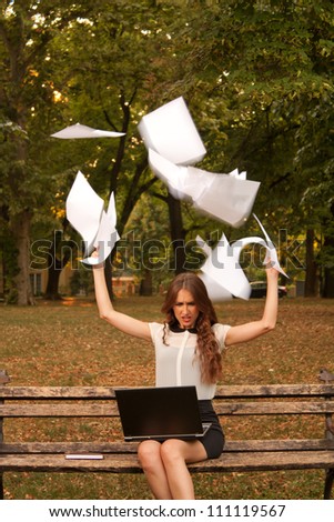 Business woman throwing paper in the air in park