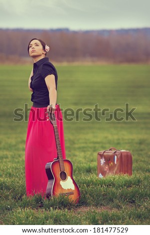 Beautiful, young girl on a meadow taking a break from a long journey