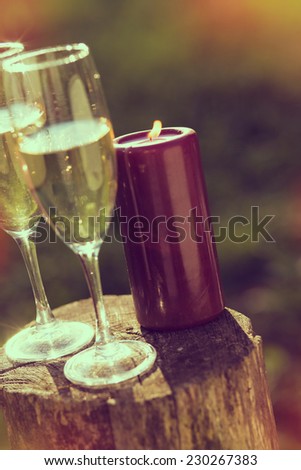 Two champagne glasses and a lit candle on the wooden fence, outdoor shoot