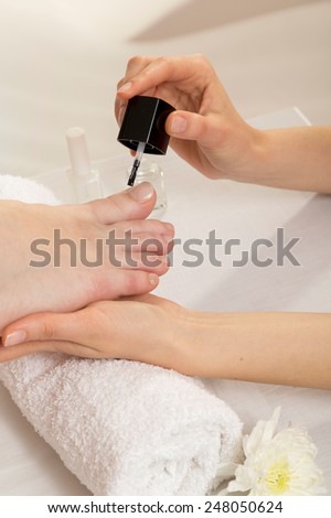 Closeup View Of A Beautician's Hand Applying Nail Varnish To Woman's Feet