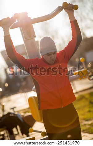 Young athlete working-out in an outdoor gym. Soft focus