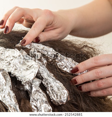 Highlighting woman client's hair in beauty parlor hairdressing salon