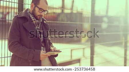 Young man surfing the internet on a tablet outdoor. Soft focus.