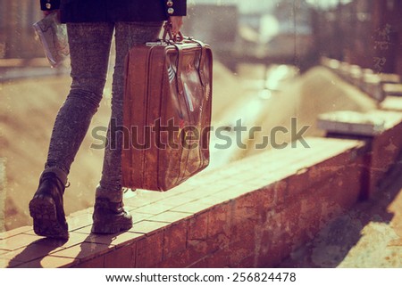 Urban young girl, walking down the street, carrying suitcase and a map.