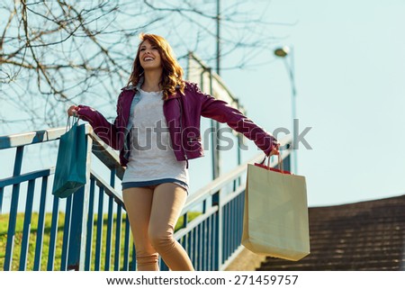 Young girl walking down the stairs and carrying shopping bags