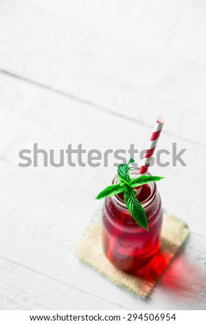 Bottle of red juice, straws and mint on the table. White copy space
