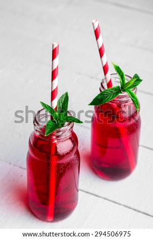 Two glasses with red juice, straws and mint on the table.
