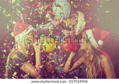 Three young people at New Year\'s Eve party on midnight blowing colorful balloons and having fun
