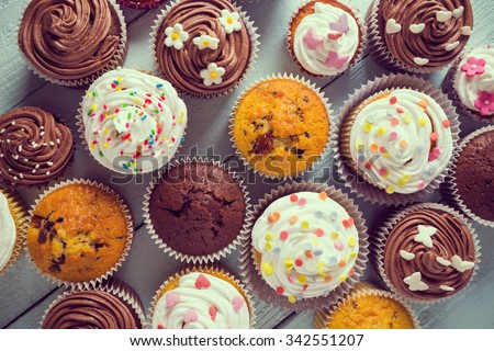 Multiple colorful nicely decorated muffins on a wooden background, top view