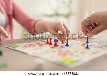 Close up of a couple in love sitting on the floor next to a table, playing ludo board game and enjoying their free time together. Focus on the red figurine