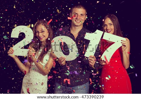 Three young friends having fun at New Year\'s Eve Party, holding cardboard numbers 2017