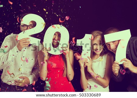 Two beautiful young couples having fun at New Year\'s Eve Party, holding cardboard numbers 2017