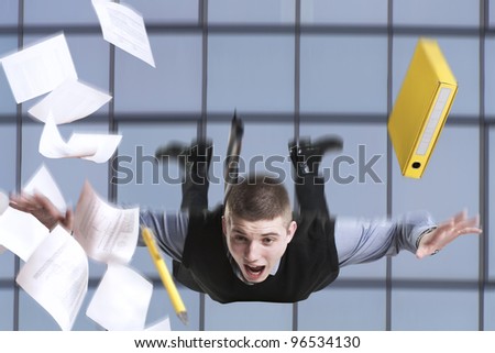 Young businessman falling from the building with his documents