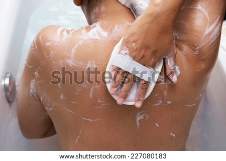 girl cleaning her body with loofah body scrub, bathroom