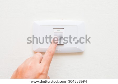 hand pressing light power switch on wall, electric
