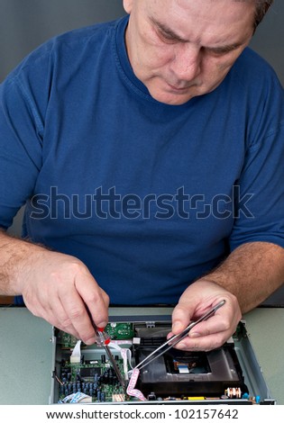 The man with a screw-driver and a tweezers repairing DVD a player