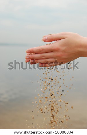 falling sand in female hands over sea