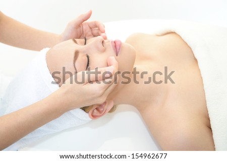 Beautiful young woman receiving facial massage in a spa salon Beautiful young woman receiving facial massage in a spa salon