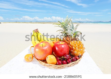 Tropical fruits in wicker basket on the sandy beach