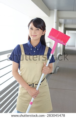 young woman with a broom sweeping the entrance.