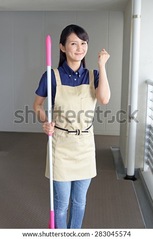 young woman with a broom sweeping the entrance.