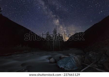 Magic night landscape with mountains, river and amazing starry sky.
