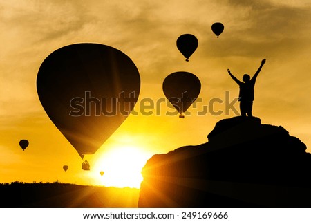 Silhouette of happy man on the sunset sky background and the flying balloons